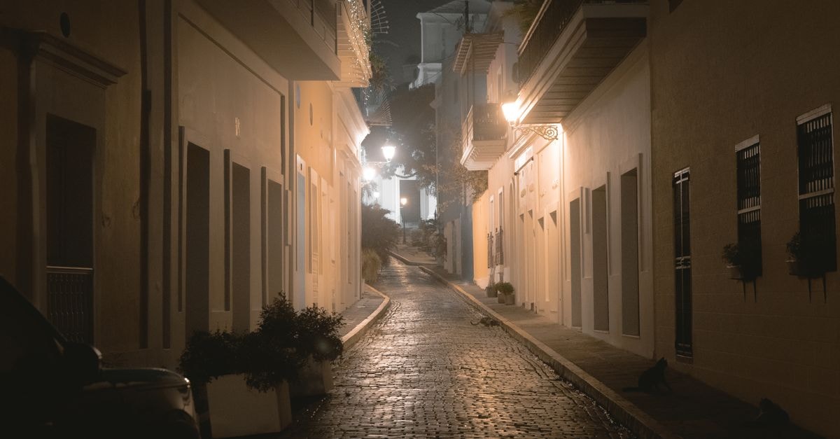 Explore the atmospheric charm of a narrow street in Old San Juan at night, showcasing historic colonial architecture.