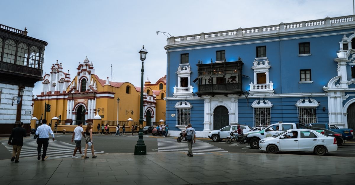 Trujillo Travel Guide: Planning Tips, Costs and Things to Do Street view of colorful colonial buildings and pedestrians in Trujillo, Peru.