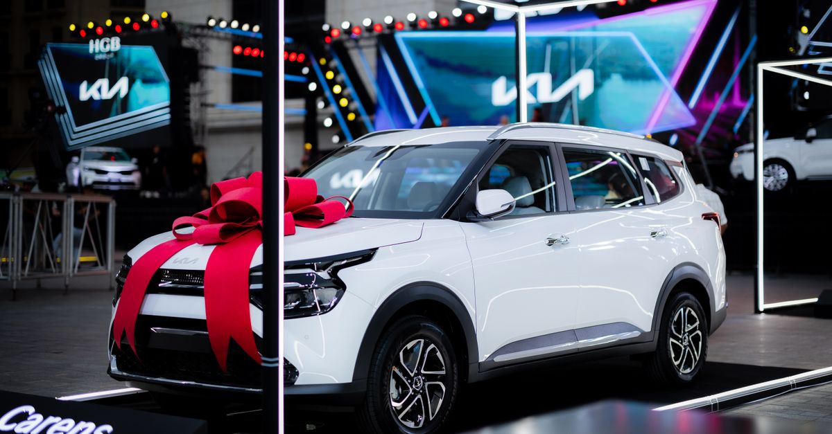 WayV and Taemin unveil new concert tours White car with a red bow on display at an automotive exhibition under bright lights.