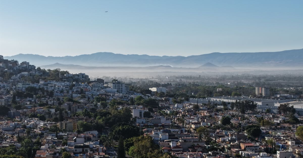 Aerial view of Guadalajara with mountains in the background, showcasing urban and natural beauty.