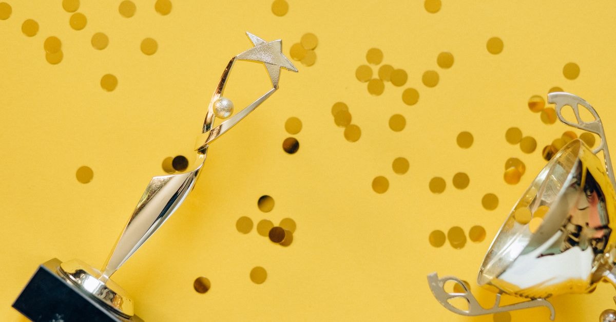 Film Festival Awards Roundup: German Lolas, Cannes Un Certain Regard and KVIFF Top Winners Golden trophy with celebratory confetti on a vibrant yellow background.