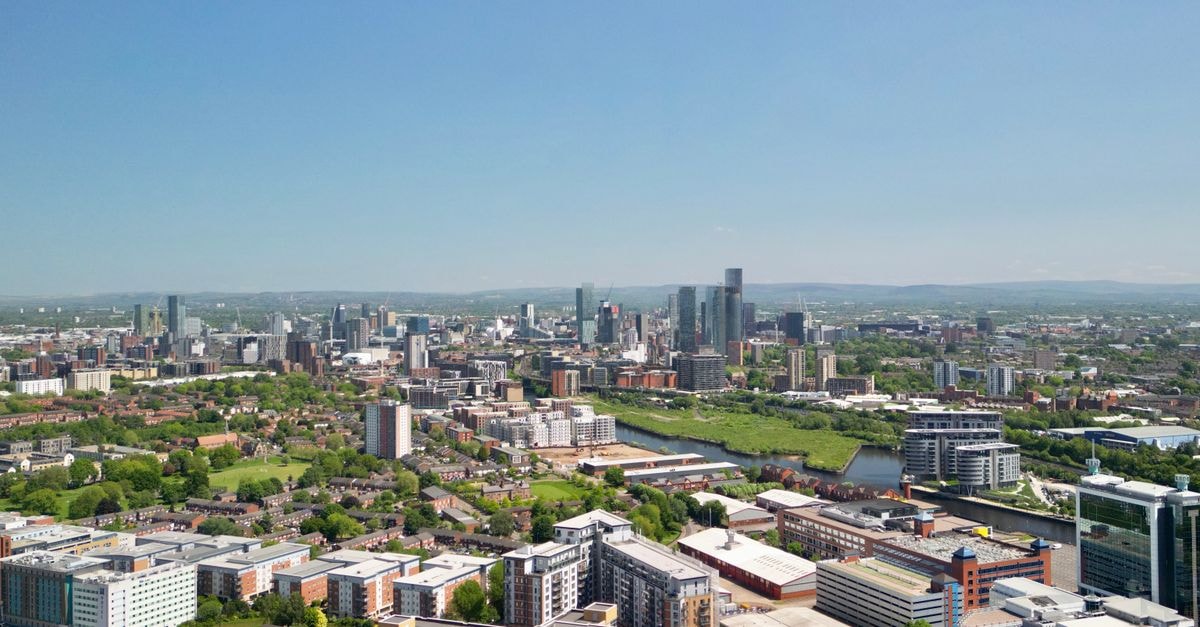 Panoramic aerial view of Manchester city with clear skies and urban landscapes.
