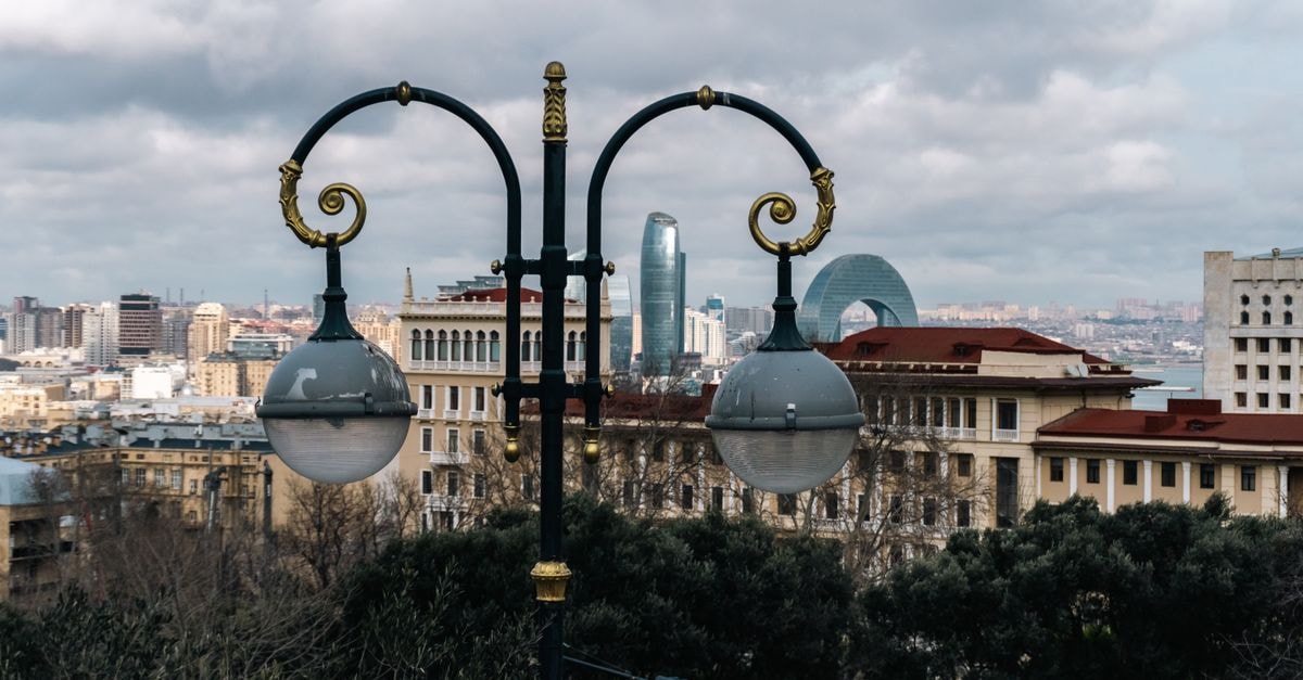 Street lamp with Baku's modern skyline, including the Flame Towers, creating a blend of old charm and modern sophistication.