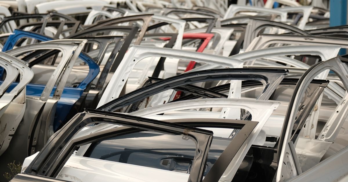 Toyota's Hybrid Push Narrows General Motors' U.S. Sales Lead to About 100,000 Vehicles A variety of car doors in different colors arranged in a junkyard setting.