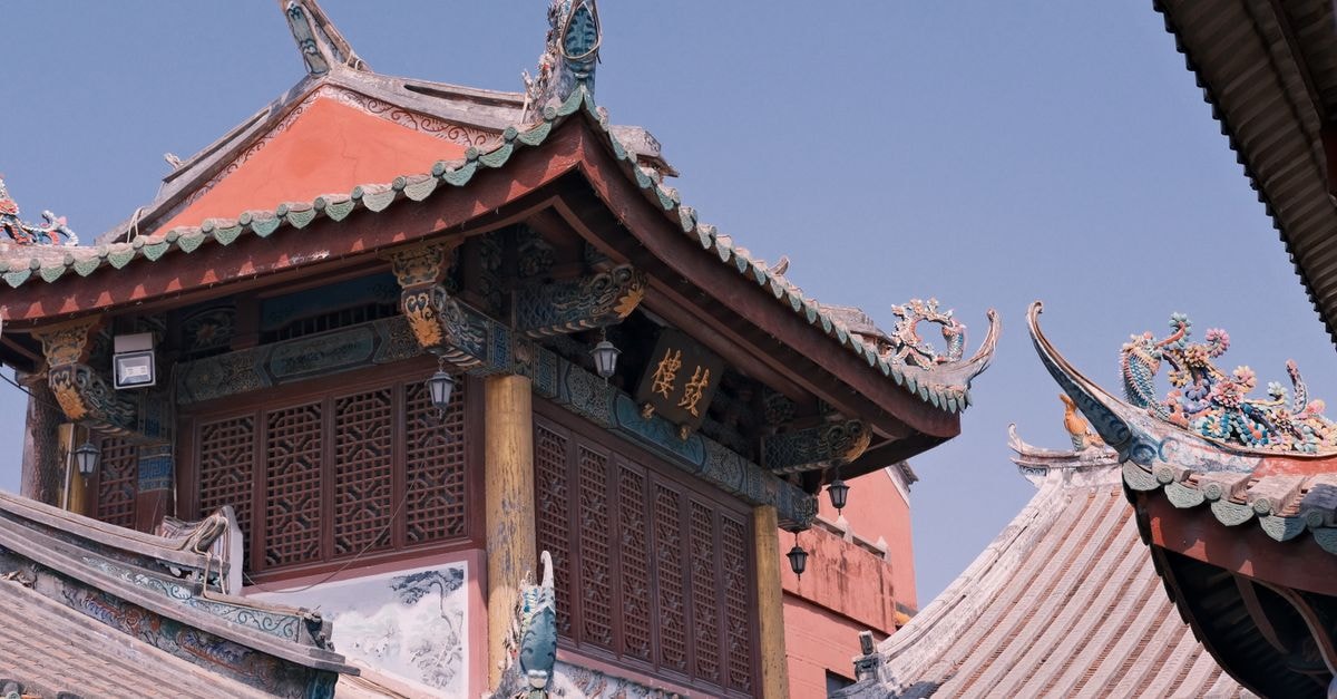 A Slow Travel Guide to Puyang: Dragons, Museums, and Henan Flavors Intricately designed traditional Asian temple rooftops seen against a clear blue sky, showcasing cultural architecture.