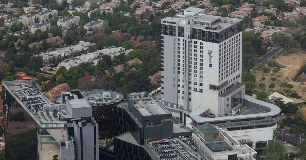 Aerial cityscape featuring modern buildings juxtaposed against suburban homes and greenery.