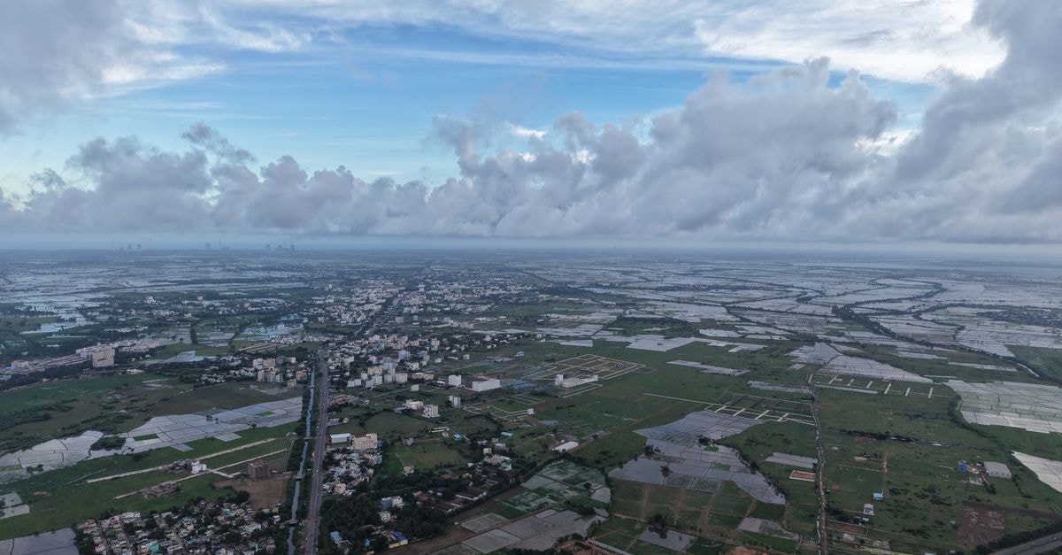 A breathtaking aerial shot capturing a vast countryside landscape with distant skyline views on a cloudy day.