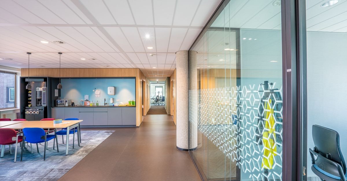 A sleek modern office space featuring colorful seating and a kitchenette in a bright, well-lit environment.