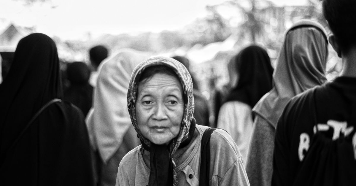 Black and white photo of an elderly woman in a crowded Pontianak street.