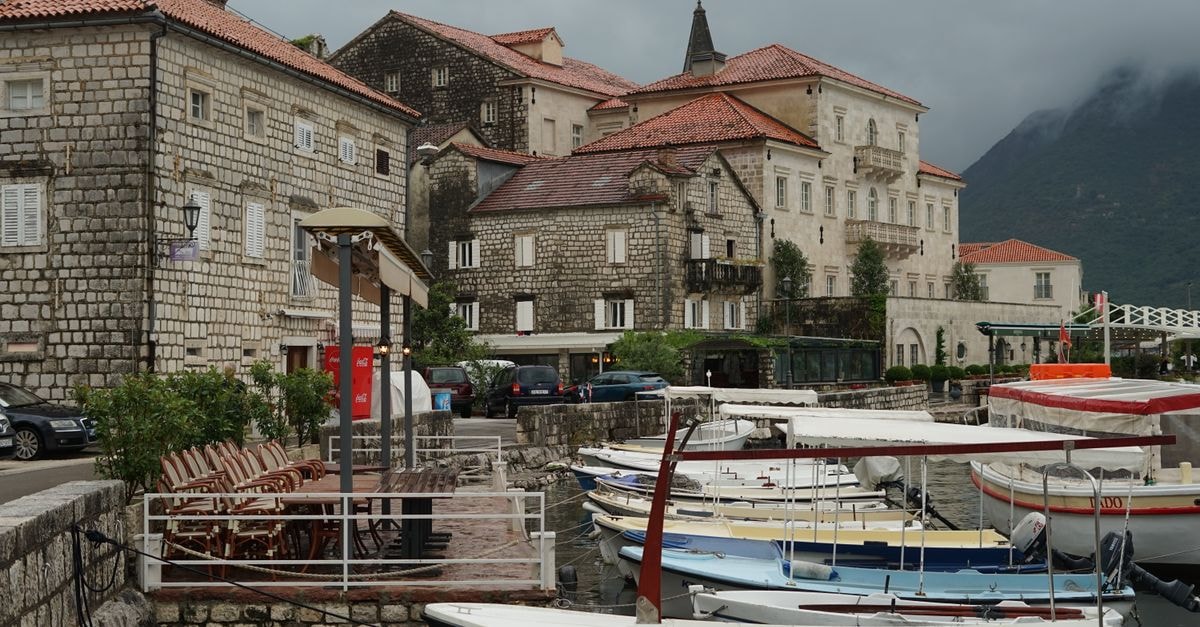 Cetinje Travel Guide: Montenegro's Old Royal Capital Charming harbor town with stone buildings, boats, and overcast sky. Perfect for travel imagery.