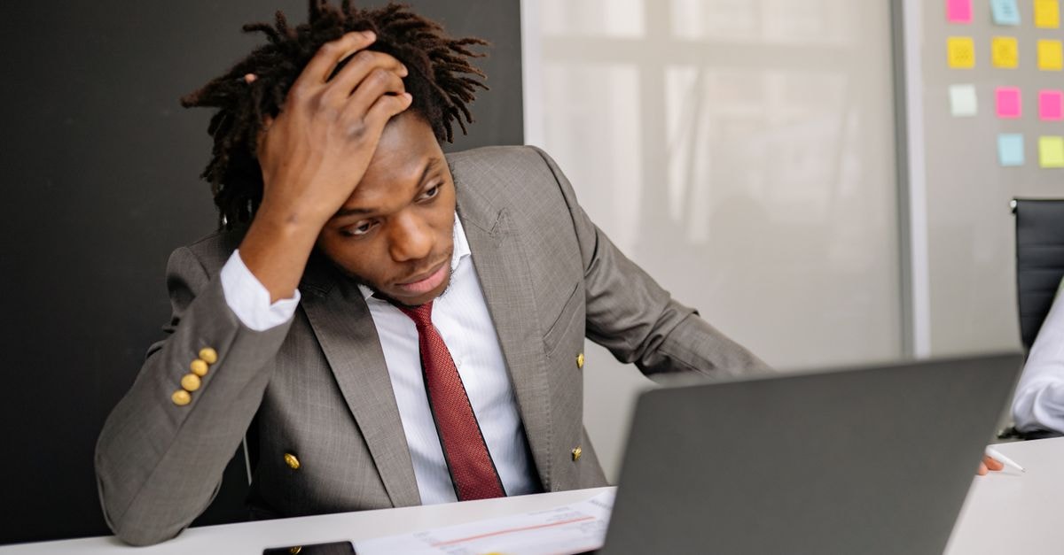 Businessman with dreadlocks looking worried while working on a laptop in the office.