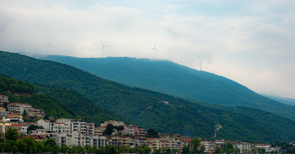 Picturesque landscape of Yalova, Türkiye featuring lush hills, wind turbines, and coastal buildings.