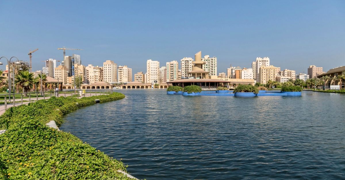 Al Mansurah Travel Guide: Planning Tips, Costs and Things to Do Scenic view of Kuwait City skyline from Al Shaheed Park with waterfront and modern architecture.