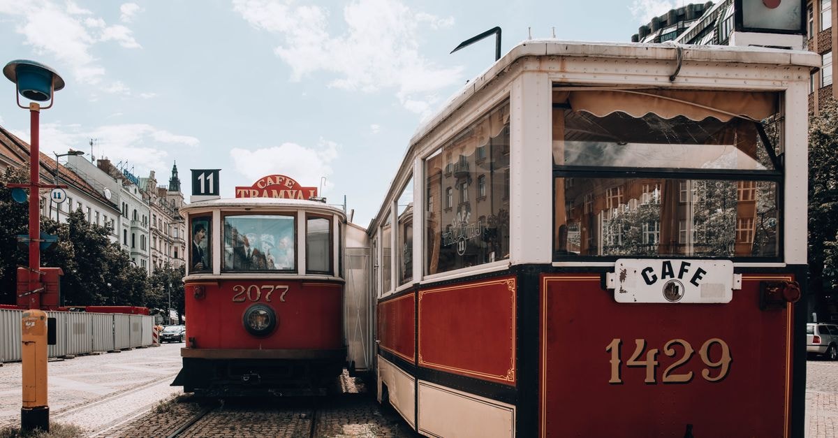 Graz Travel Guide: Old Town Charm, Tram Days, and Styrian Plates Charming vintage trams parked by a café in Prague, showcasing urban life and classic transport.