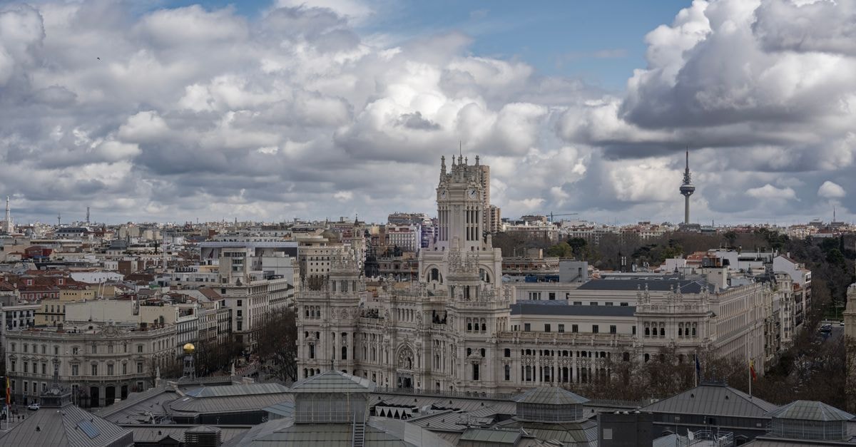 Hostal Madrid in Madrid: A 19th-Century Stay Between Sol and Plaza Mayor Aerial view of Madrid featuring the prominent Palacio de Cibeles under a cloudy sky.