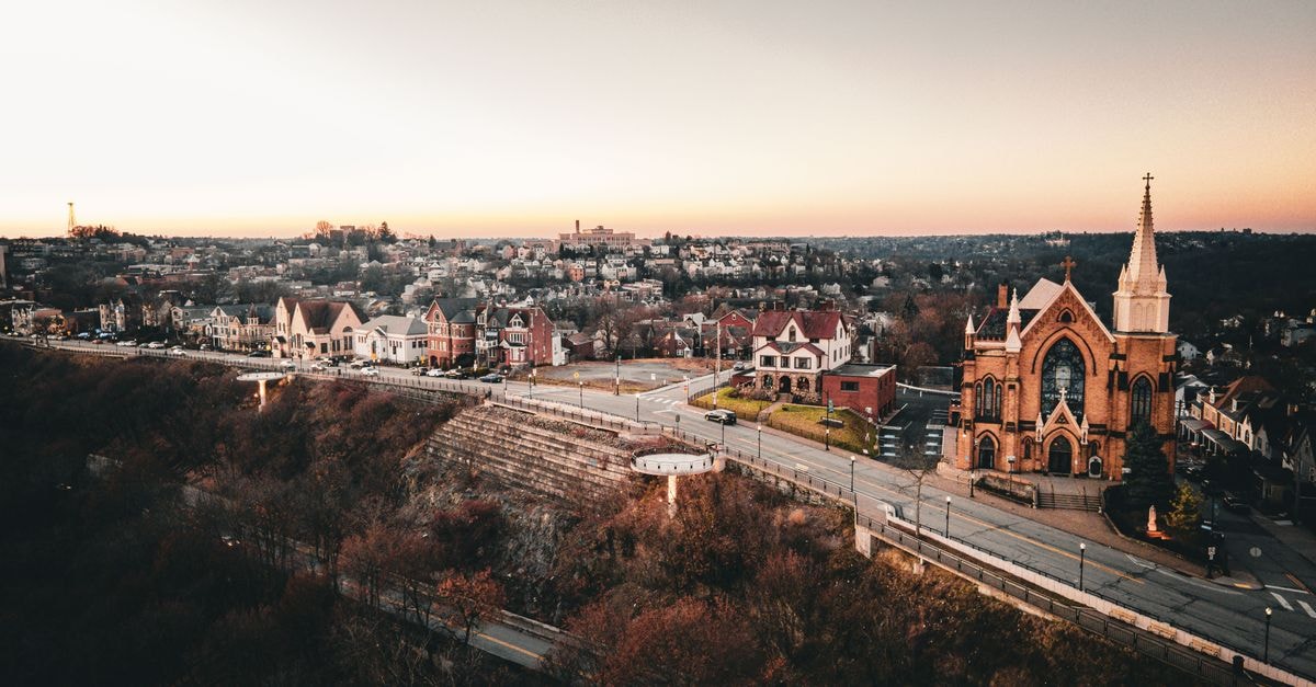 Omni William Penn Hotel, Pittsburgh: A 1916 Landmark Reimagined Stunning aerial view of Pittsburgh at sunset, showcasing a historic church and charming neighborhood.