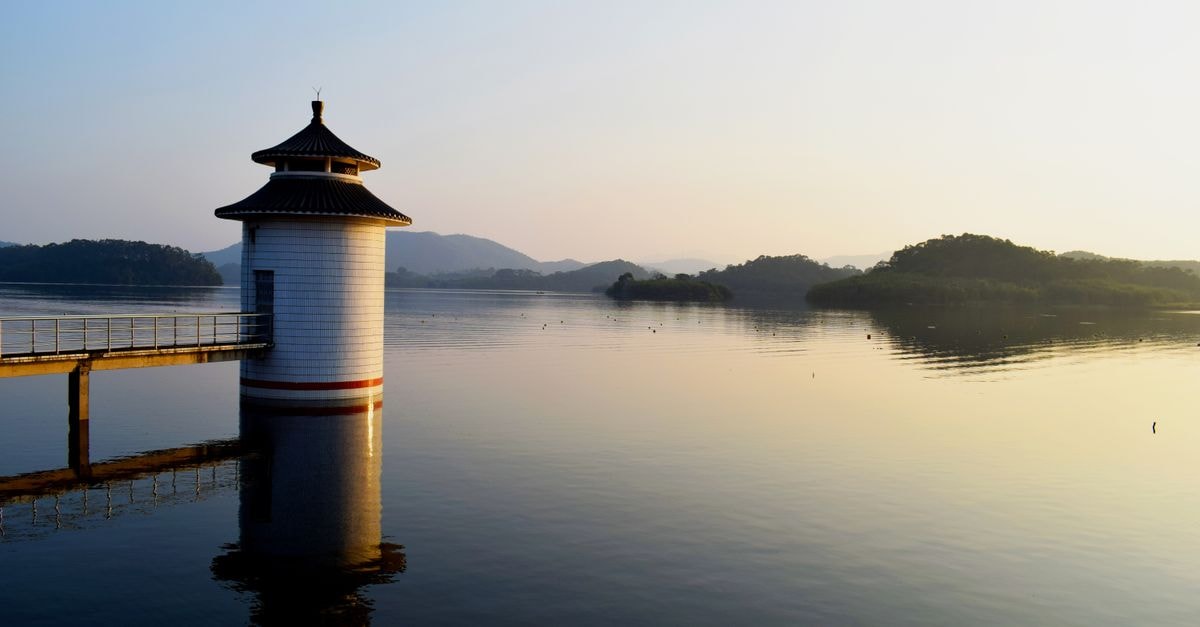 Yueyang Travel Guide: Tower Lights, Lake Air, and Easy Wandering Serene lake scene with a tower and scenic reflections at sunrise, perfect for travel and nature themes.
