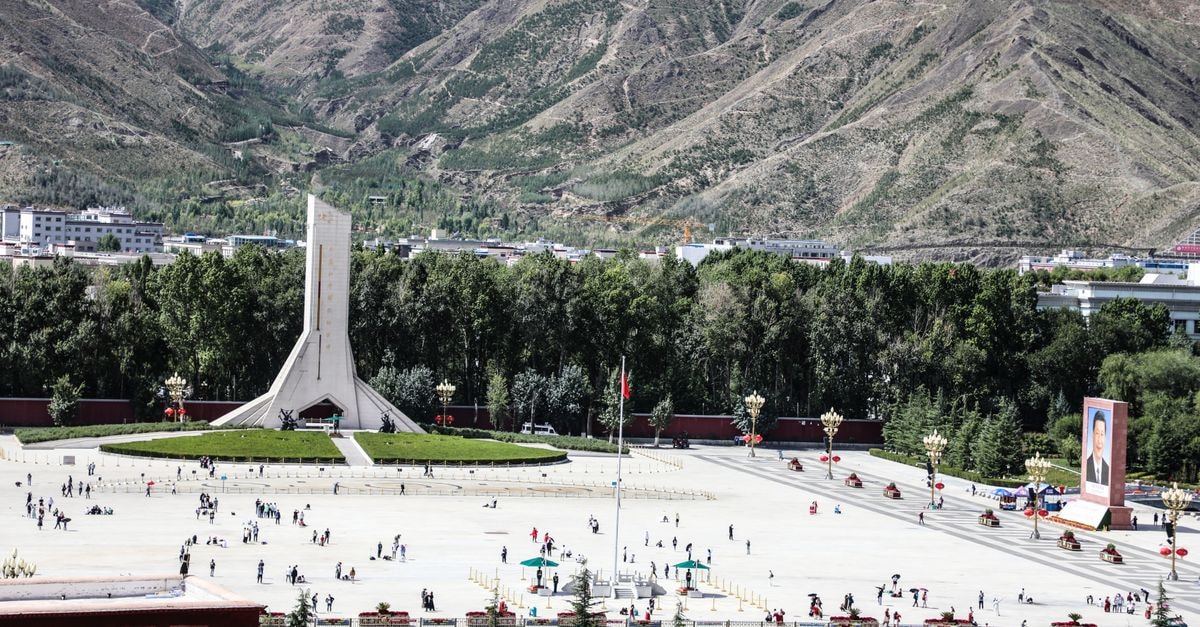 Yinchuan Travel Guide: Planning Tips, Costs and Things to Do City square bustling with people, featuring a prominent monument and scenic mountain backdrop.