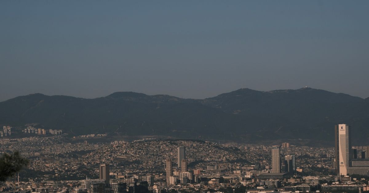 A panoramic view of Izmir's skyline against a mountain backdrop under a clear sky.