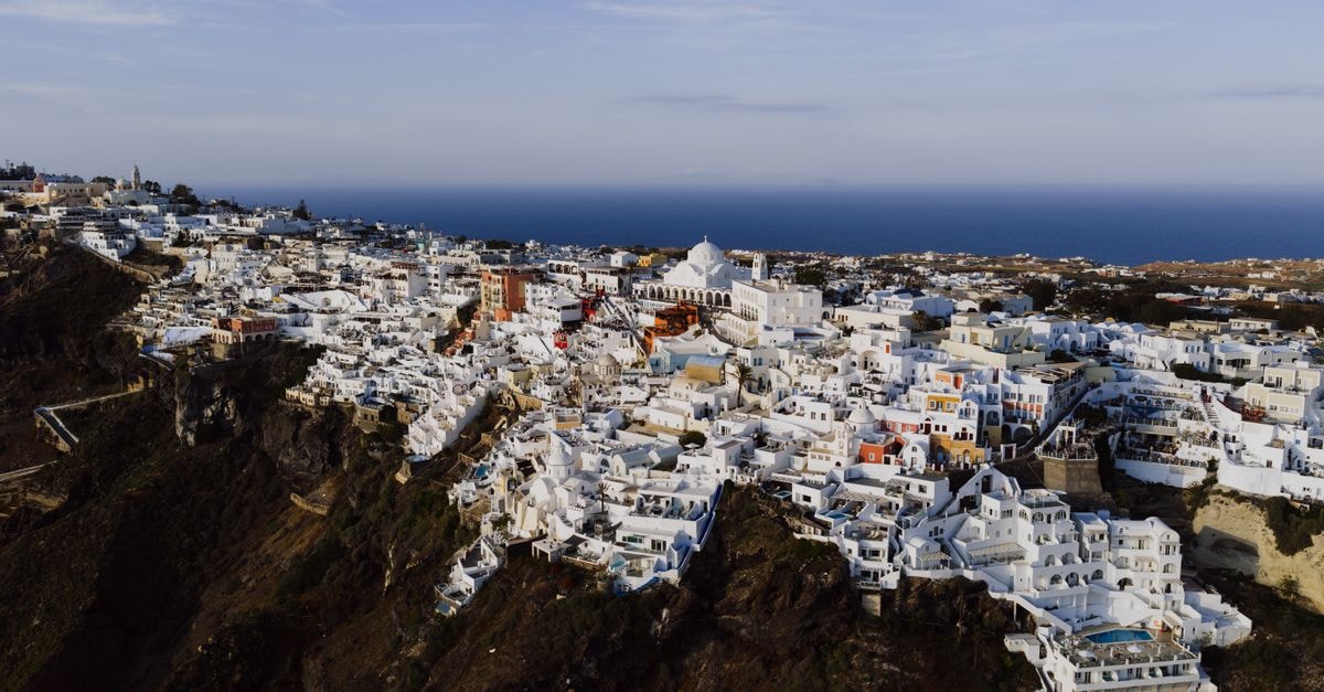 Athina Luxury Suites in Fira: Caldera-Cliff Suites with Infinity Pool and Volcano Views Stunning aerial view of Fira's iconic white architecture against the Aegean Sea.