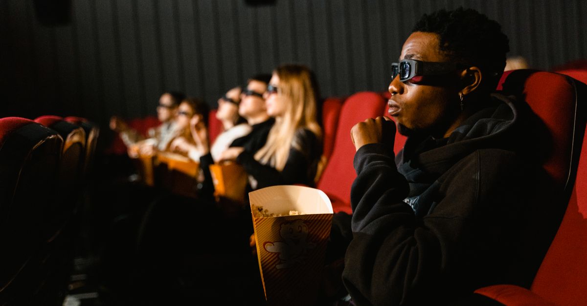 "The Odyssey" tops North American box office with $87M second weekend A group of diverse adults wearing 3D glasses enjoying a movie indoors.