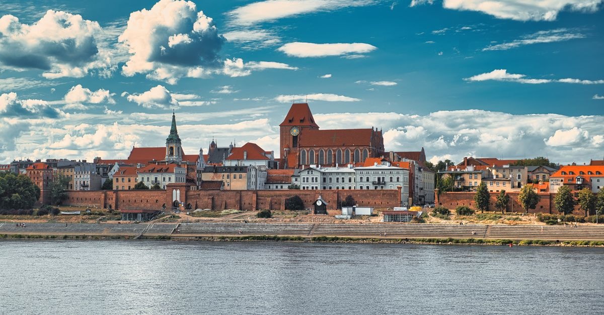 Slow Days in Bydgoszcz: A Polish River City Travel Guide Scenic view of Toruń's medieval architecture across the Vistula River under a vibrant sky.