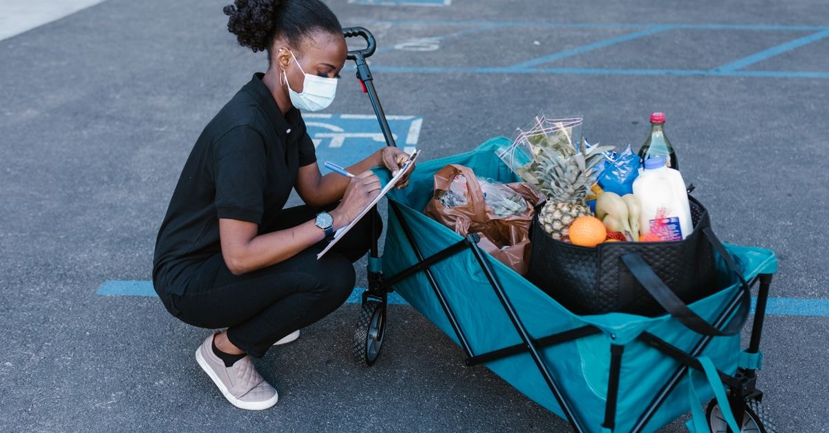 Maplebear (Instacart): Cash-Generative Marketplace Trading Below a Constructive Ten-Year Fair Value A woman in a face mask checking a clipboard while squatting next to a delivery cart full of groceries.