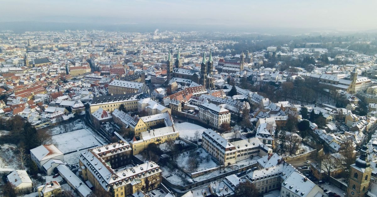 City Hostel in Augsburg: A Central Stay Across from the Fuggerei A stunning aerial view of Bamberg, Germany covered in snow, showcasing historical architecture.