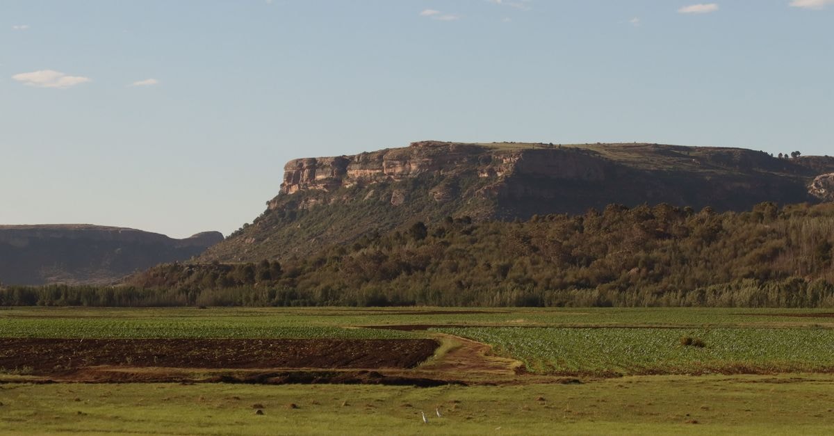 Serene view of Lesotho's lush fields and rugged mountains under clear blue skies.