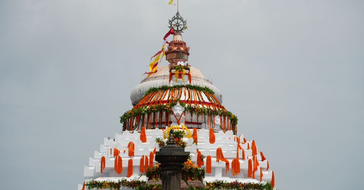 Panthanivas Puri in Puri: A Marine Drive Retreat Near Golden Beach A beautifully decorated Indian temple dome with vibrant flowers and flags under a clear sky.