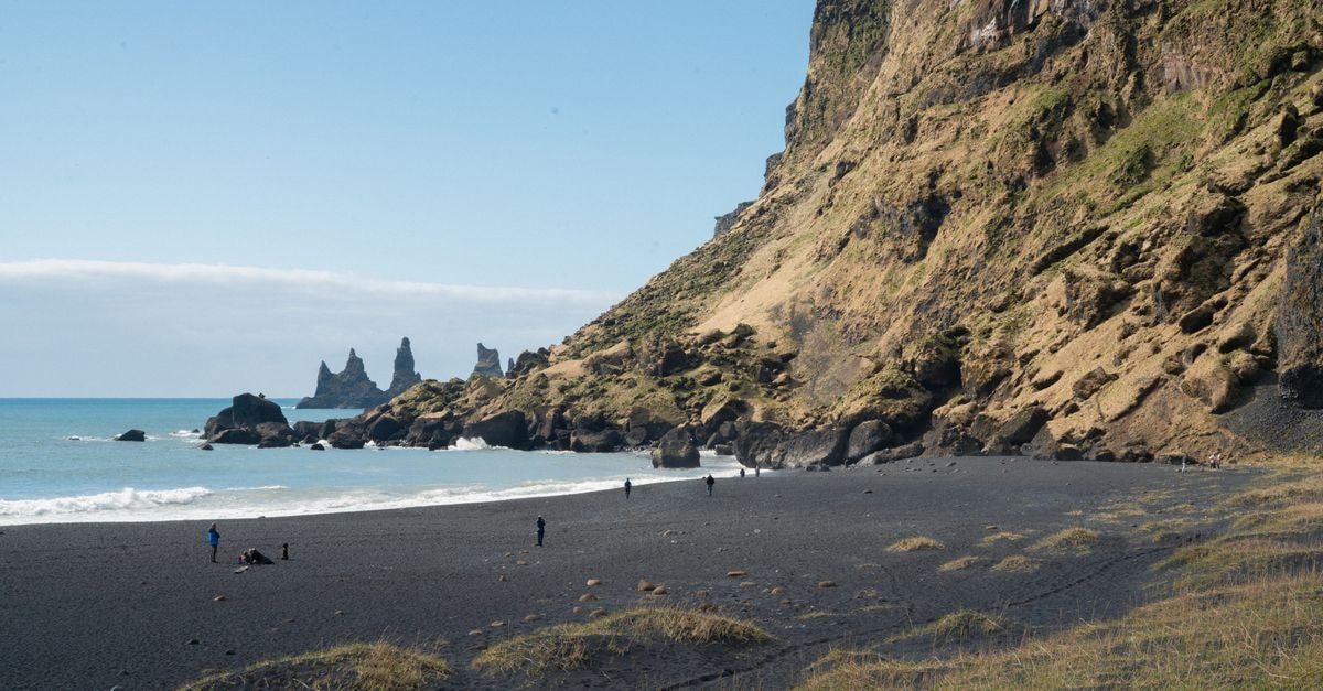 Beautiful view of Reynisfjara Beach in Iceland, featuring black sand and striking basalt columns against the blue ocean.