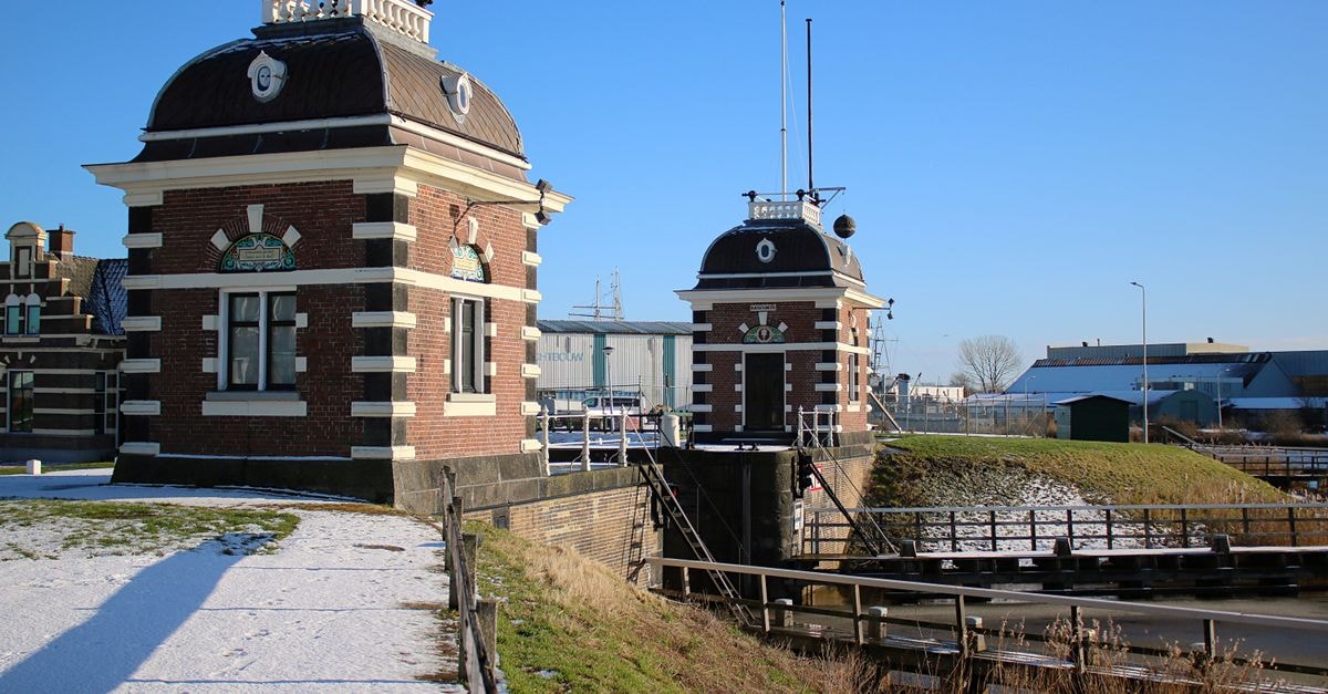 Leeuwarden travel guide: a slow look at Friesland's capital View of the historic Lemmer lock in Netherlands during winter with snow and blue skies.