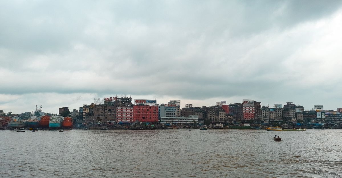 Discovering Dhaka: A Thoughtful Travel Guide to the Megacity Urban skyline along the Buriganga River in Dhaka, showcasing an overcast sky and bustling riverside scene.