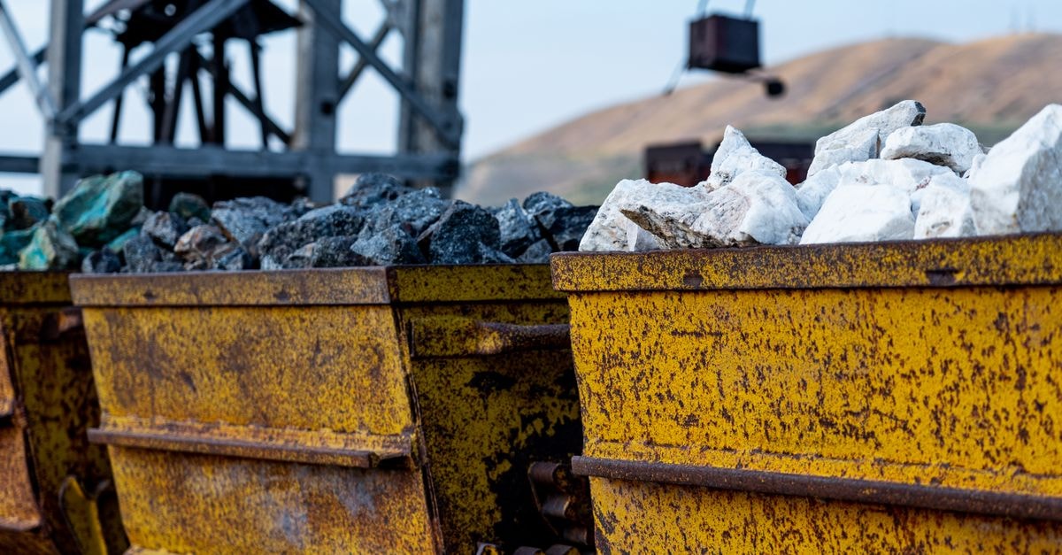 Canada Nickel wins federal approval for Crawford, set to be Western world's largest nickel mine Close-up of rusty mining carts filled with various minerals in an industrial setting.