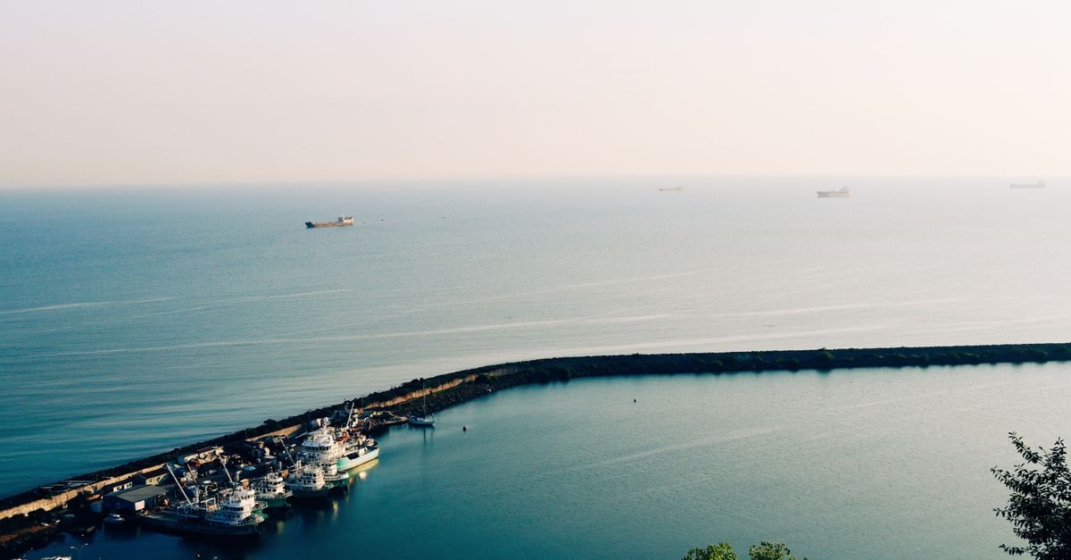 A tranquil aerial view of Samsun harbor's ships docking, with the vast Black Sea beyond.