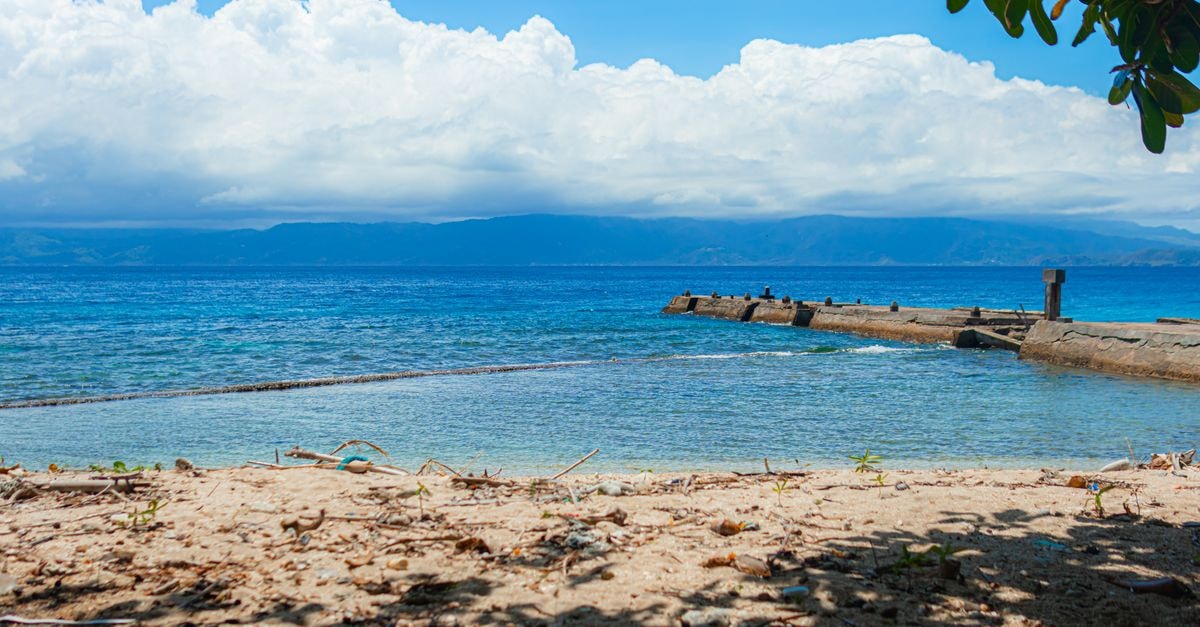 Point Fortin Travel Guide: Planning Tips, Costs and Things to Do Tranquil beach scene featuring a pier, clear sea, and cloudy sky, perfect for summer landscapes.