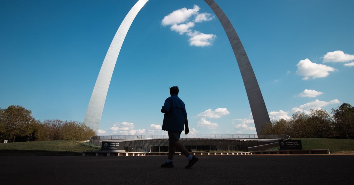 Le Méridien St. Louis Downtown: A 1913 Classic on Pine Street Silhouette of a person walking by the iconic Gateway Arch under a clear blue sky.