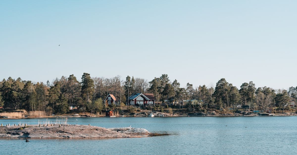 Pori Travel Guide: Planning Tips, Costs and Things to Do View of serene lakeside houses surrounded by forests and clear water, perfect for nature lovers.