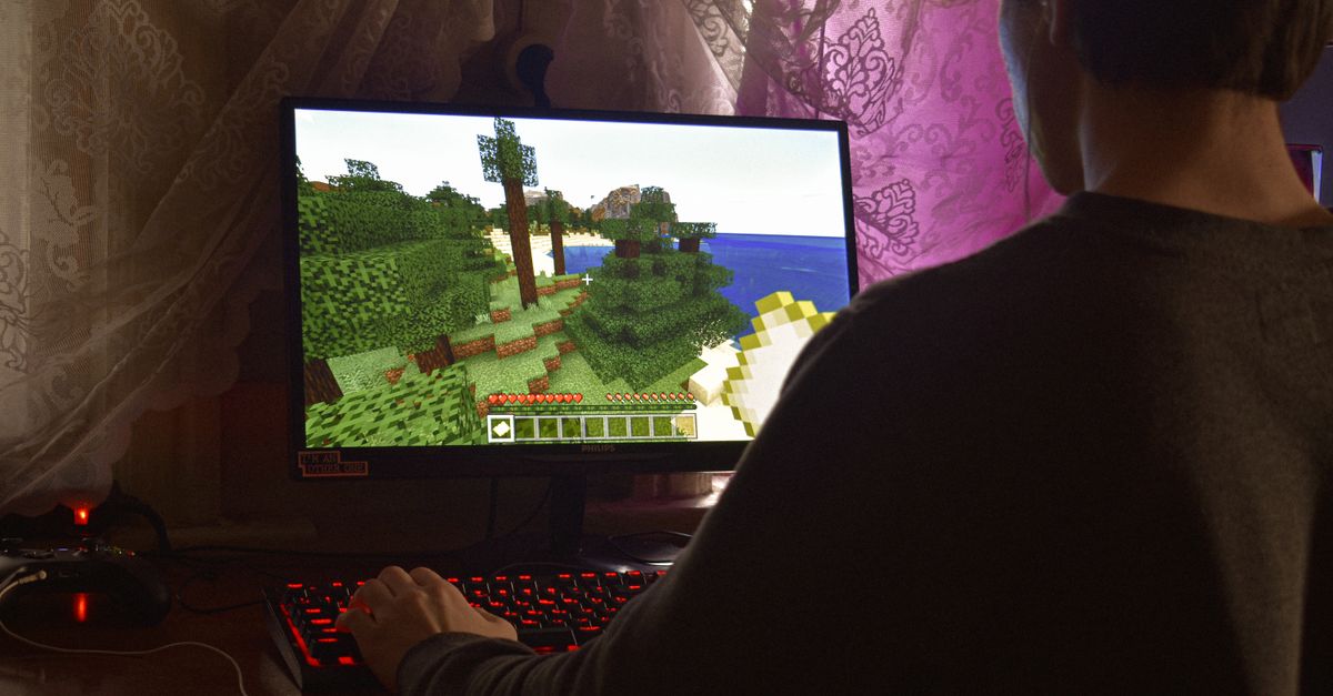 Minecraft system requirements rise after 17 years; D&D and World of Warcraft crossover leaks ahead of Gen Con A young man intensely playing a PC video game indoors. Capturing the essence of technology and concentration.