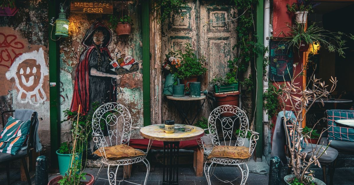 Korçë Travel Guide: Coffee, Frescoes and Slow Mountain Charm Cozy patio of a café in Istanbul with rustic decor, potted plants, and artistic mural.