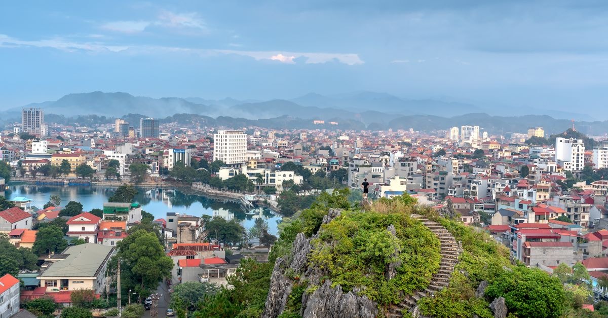 Thanh Hoa Hotel, Thanh Hóa — A Quang Trung Stop Near Jollibee Aerial view of Lang Son cityscape with lush green hill and distant mountains under a cloudy sky.