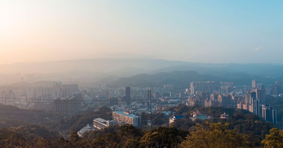 7 Days Inn in Qingyuan: A Practical Stay on Nanmen Street A stunning aerial view of a cityscape with mountains and trees during sunset.