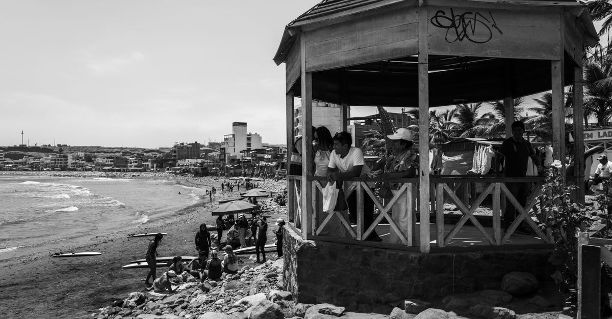 Monochrome view of people gathered by a gazebo on Huanchaco beach, Peru.