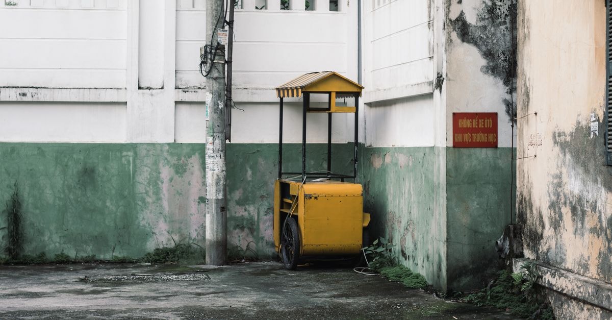 Ogbomoso Travel Guide: Quiet Corners of an Old Yoruba City A vintage yellow cart stands idle in a quiet urban alley corner, surrounded by weathered walls and soft sunlight.