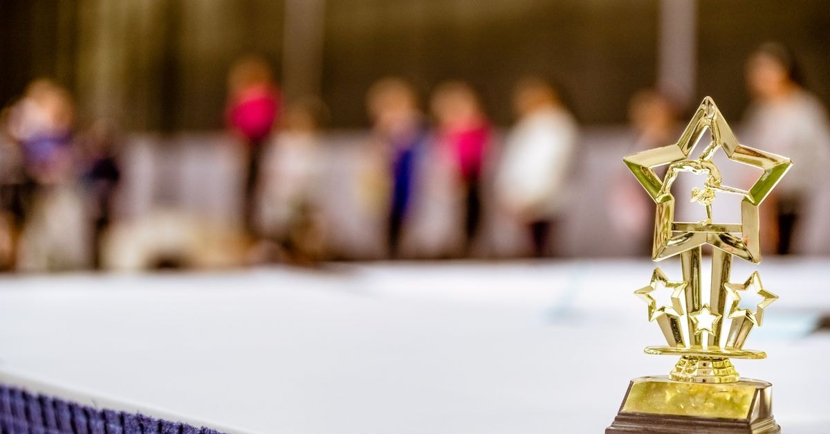 Dancing with the Stars Season 35 to Premiere September 15 With Bigger Cast, Producers Reveal at First-Ever Convention Star-shaped trophy on a table with blurred people in the background at an indoor event.