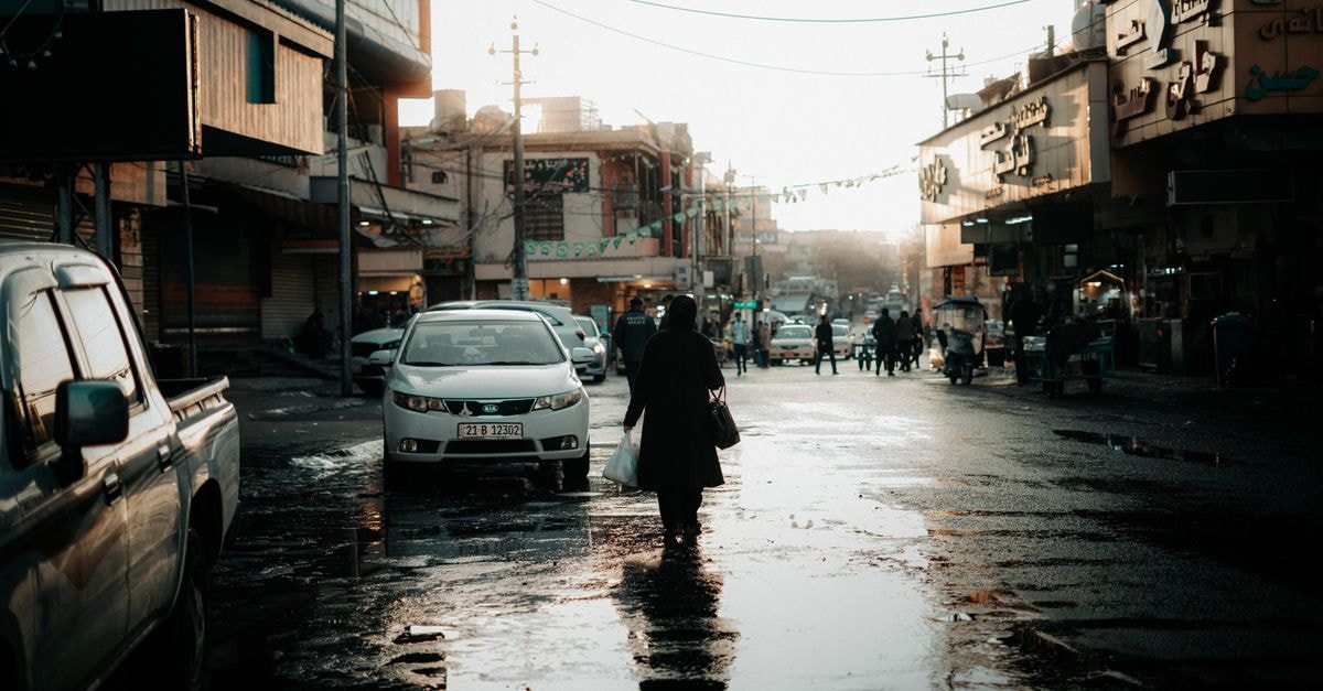 Lively street in Sulaymaniyah during sunset with people and vehicles. Urban daily life captured artfully.