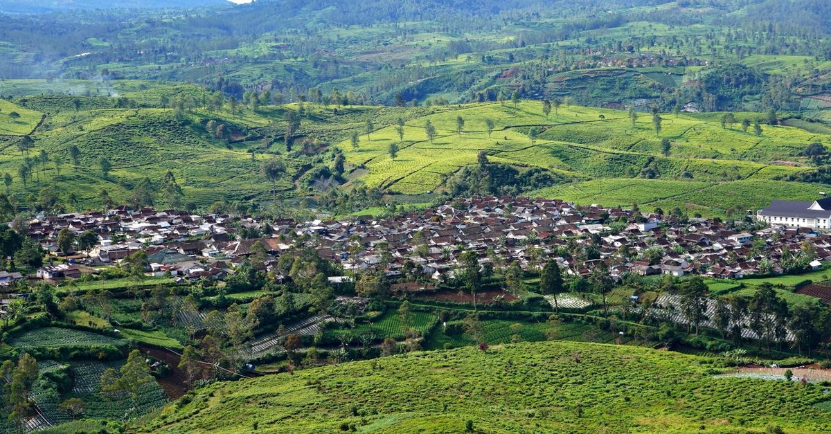 Captivating aerial photograph showcasing a verdant village nestled amidst rolling hills and tea plantations.