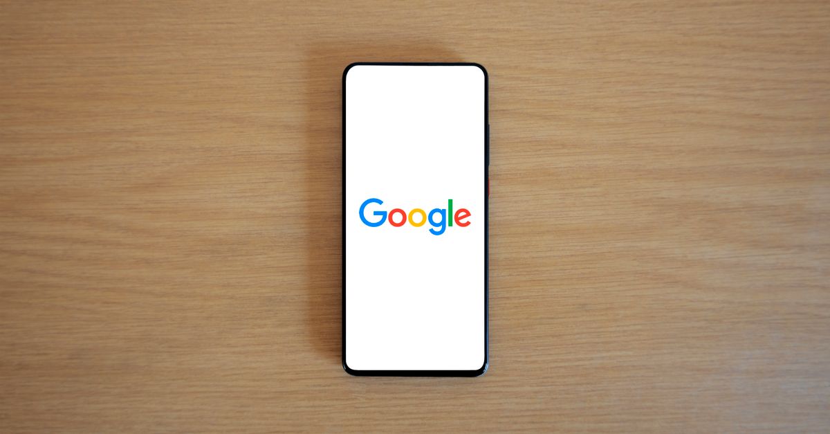 Google expands Gemini lineup with three new models and broader Spark access A smartphone displaying the Google homepage on a wooden surface, viewed from above.