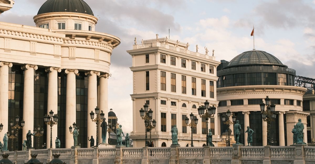 A beautiful view of neoclassical buildings and statues on a bridge in Skopje at sunset.