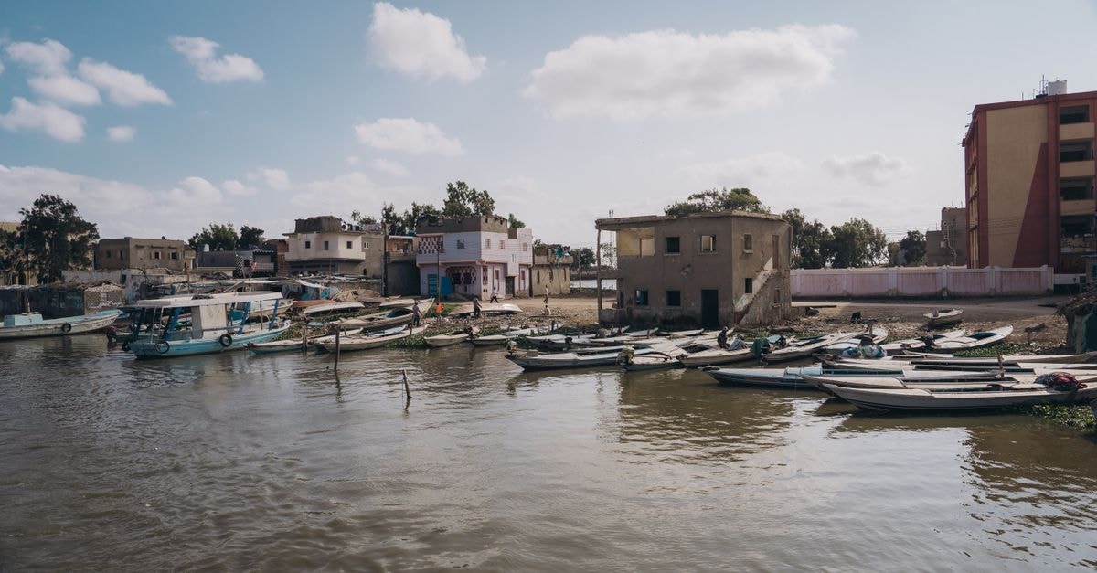 Platinum Hotel in Basra: An Elegant Stay on Al-Jazair Street Tranquil waterfront scene in Kafr El-Shaikh, Egypt with boats and historic buildings.